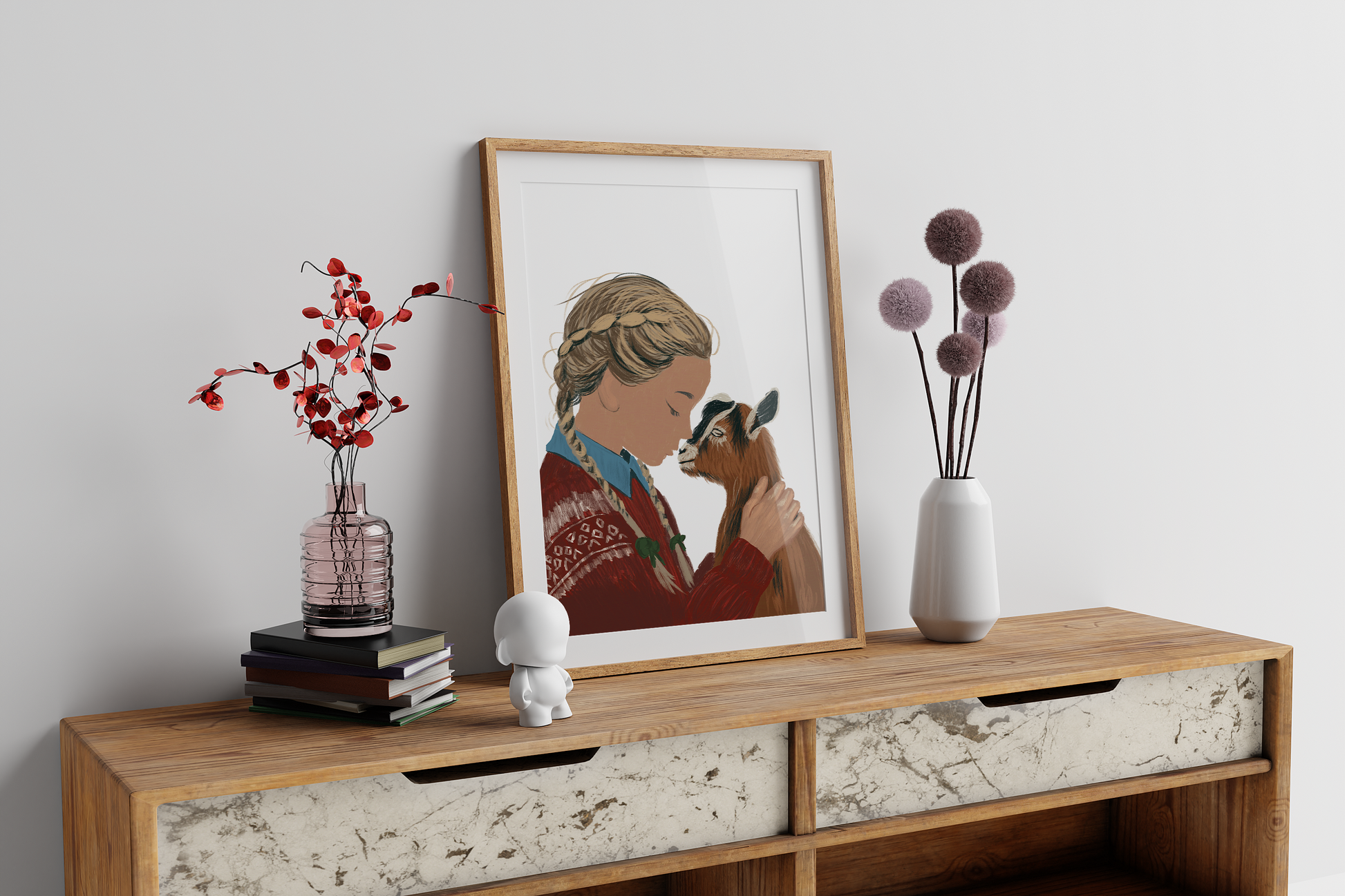A modern sideboard decorated with a framed printable digital painting of a girl embracing a goat, accompanied by artistic vases and books.