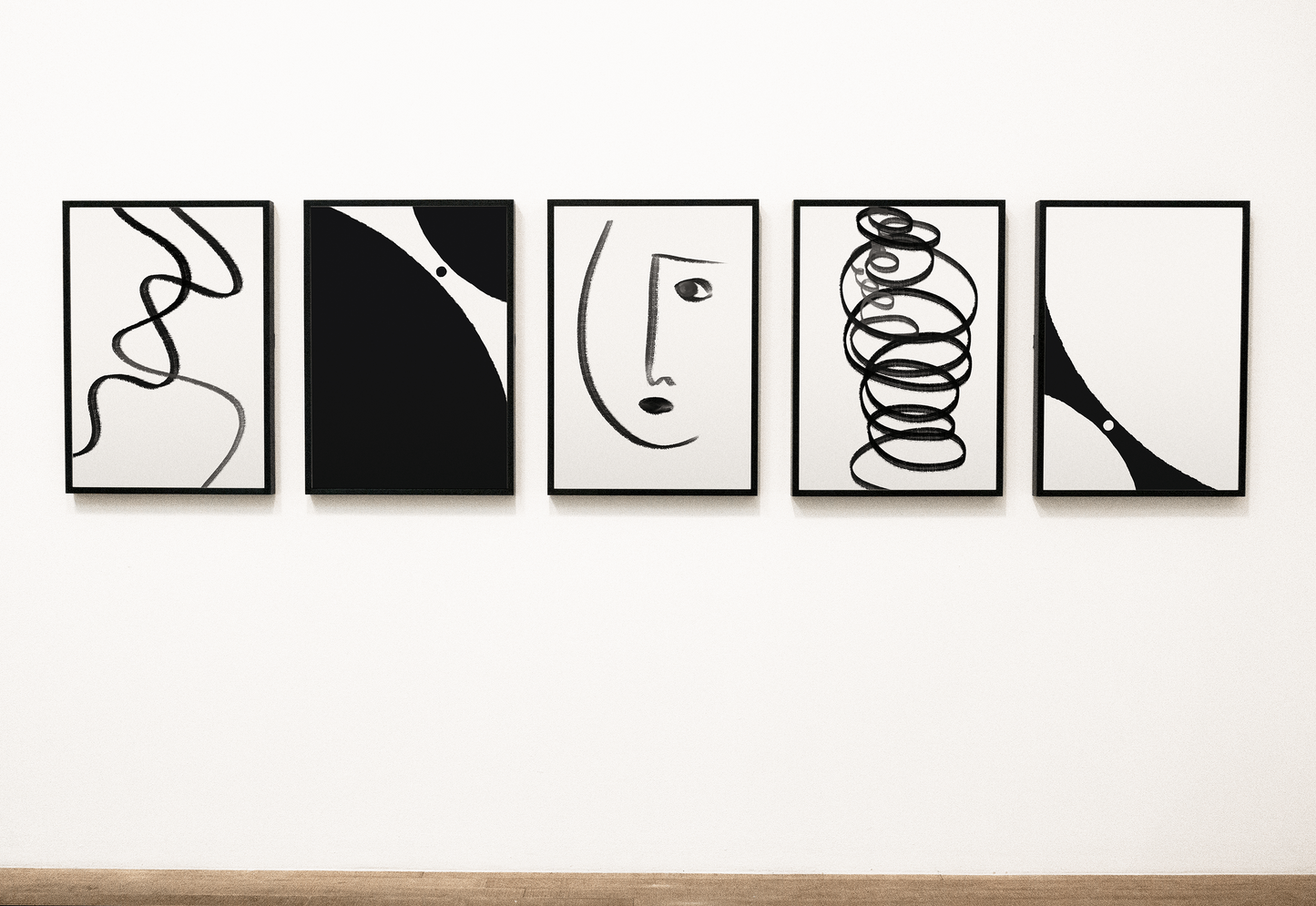 Gallery wall featuring a series of five framed abstract black and white artworks, with various geometric and organic shapes creating a cohesive modern art collection.