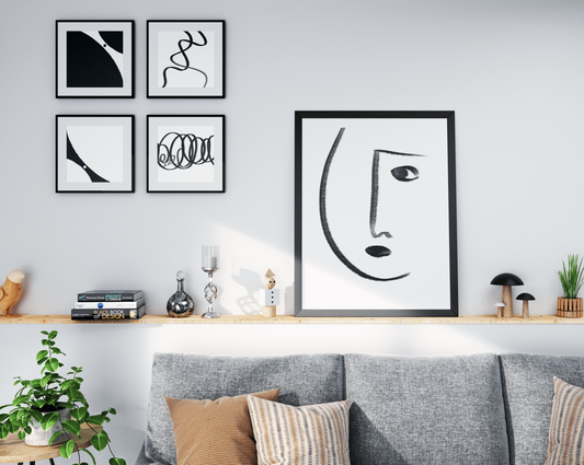 Modern living room with a collection of abstract black and white artwork arranged above a wooden shelf, complementing the minimalist decor and gray couch