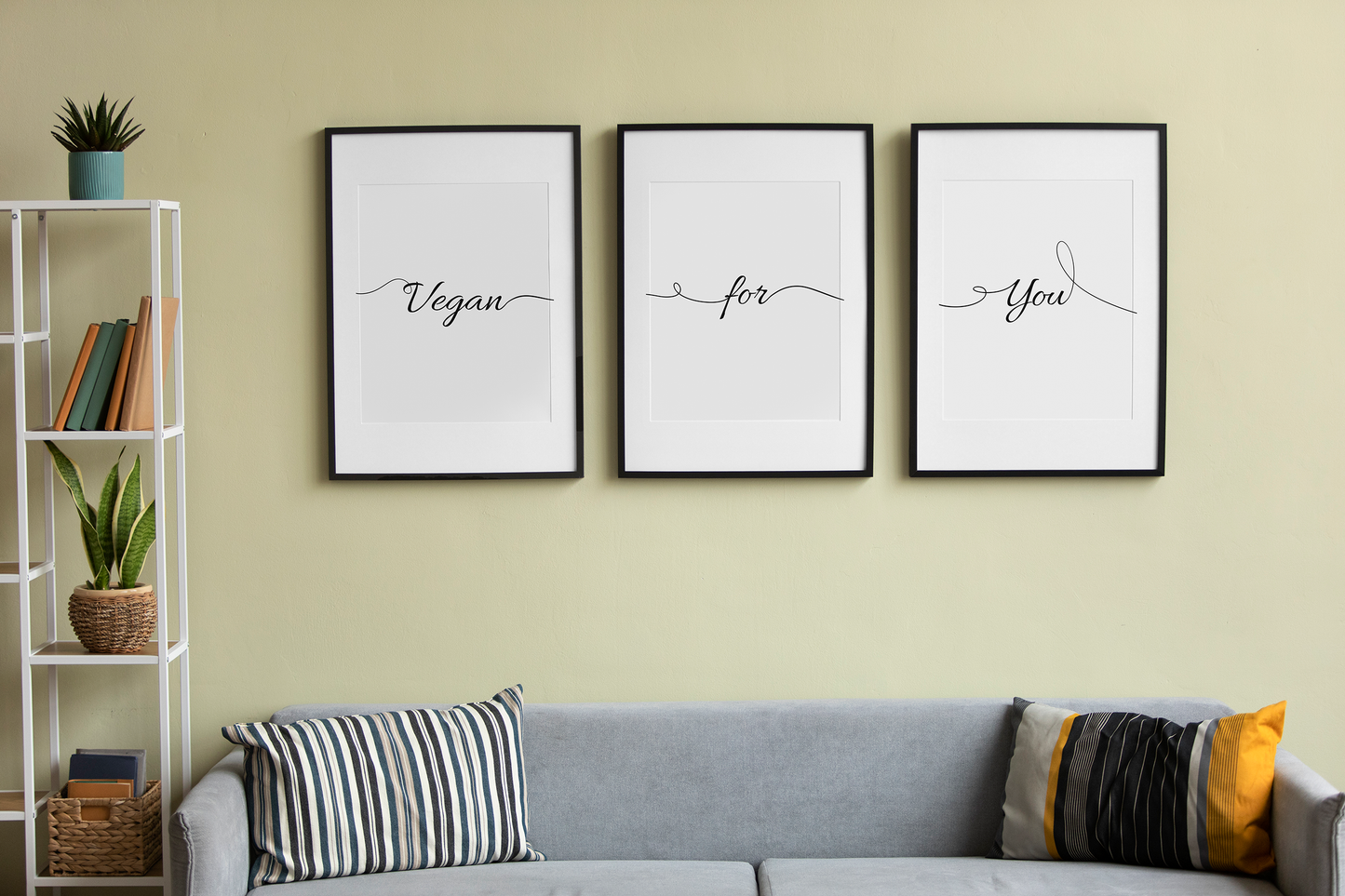 Modern home setup with a trio of printable digital paintings on the wall reading 'Vegan', 'for', 'You' above a comfortable sofa, blending art with home comfort.