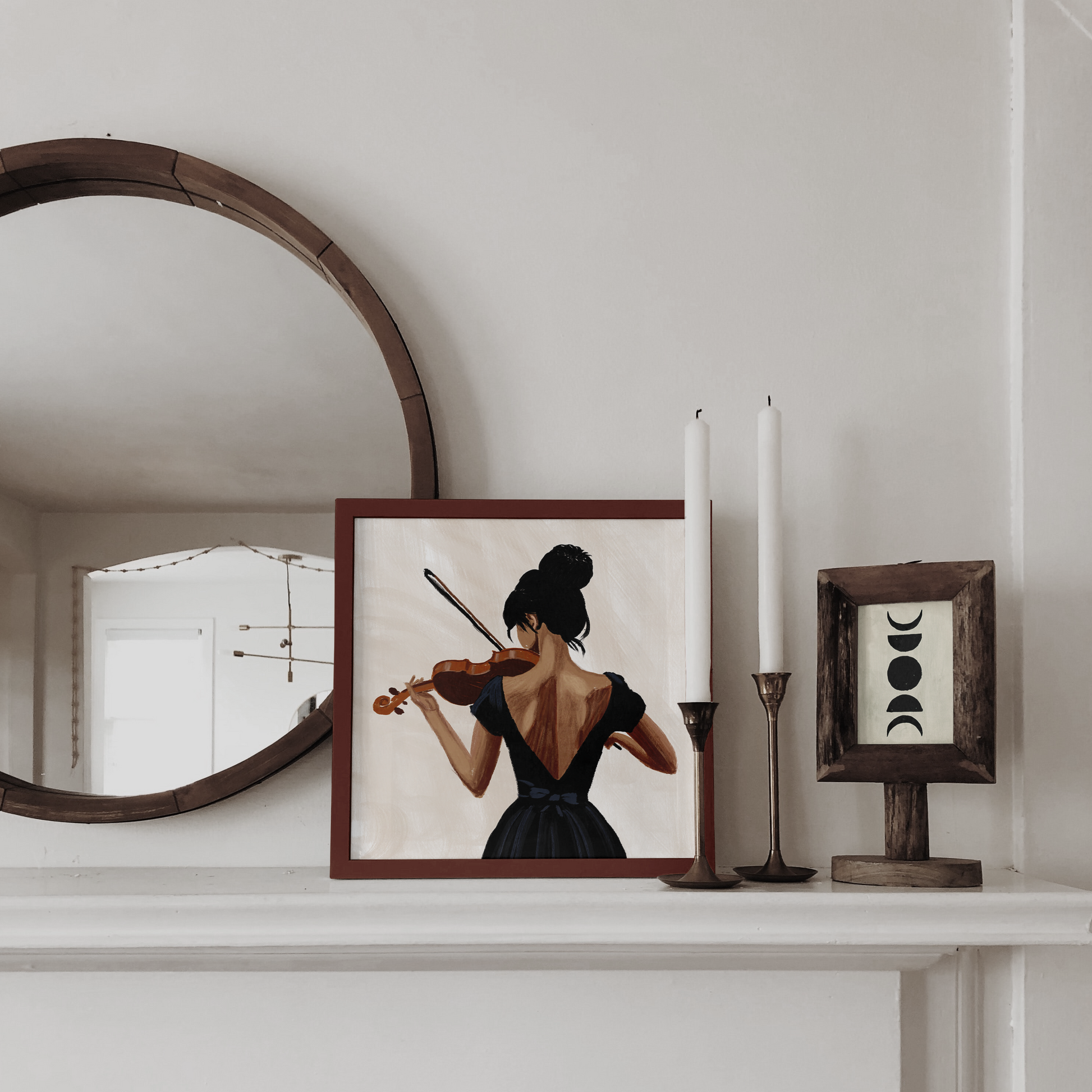 Classic mantlepiece arrangement with a framed image of a woman with a violin, reflecting a blend of traditional and modern decor elements in the room